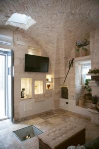 a living room with a tv on a stone wall at Relais l’Antico Pozzo in Martina Franca