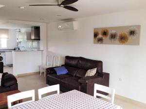a living room with a brown couch and a table at Residencial Olival-Acceso privado playa por jardín in Oliva