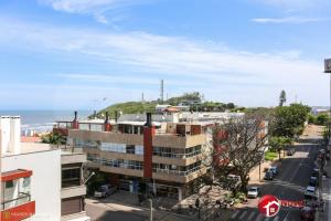 Vistas a una calle con un edificio y al océano en Ótimo apartamento na Prainha Torres/RS, en Torres