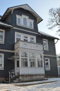 een groot zwart huis met een witte veranda bij Ferienwohnung "Auszeit" in Tabarz