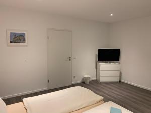 a white bedroom with a bed and a television at Zentrum Appartment Neuburg in Neuburg an der Donau