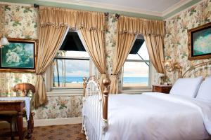 Doryman's Oceanfront Inn في شاطئ نيوبورت: غرفة نوم بسرير ونافذة كبيرة