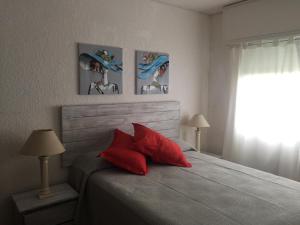 Un dormitorio con una cama con almohadas rojas y una ventana. en FLATS ON THE BEACH BALCONADA II, en La Paloma