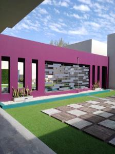 una casa rosa con un césped verde delante de ella en garden33 en Chivilcoy