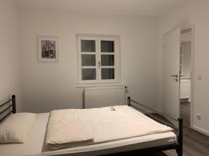 a bed in a white room with a window at Zentrum Appartment Neuburg in Neuburg an der Donau