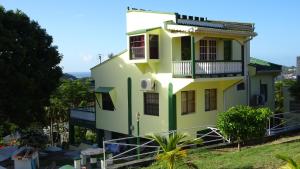 a yellow and green house with a balcony at Little Palace BNB in Saint Georgeʼs