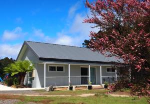 uma casa com um telhado cinzento e uma árvore com flores cor-de-rosa em Erriba House em Erriba