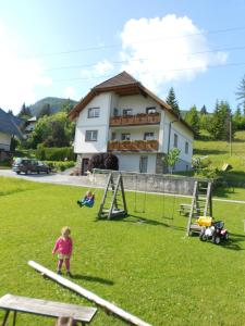 a child playing in a playground in front of a house at Haus Moni in Mauterndorf