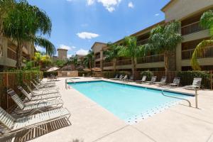 a swimming pool with lounge chairs in front of a building at Siegel Select Casa Grande in Casa Grande