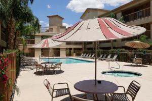 un patio con sombrilla, sillas y piscina en Siegel Select Casa Grande en Casa Grande
