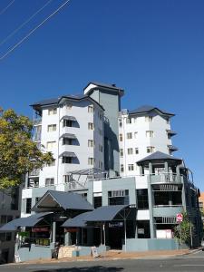 a large white building with black umbrellas in front of it at The Sedgebrook On Leichhardt in Brisbane