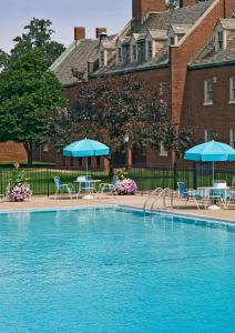 einem Pool vor einem Gebäude mit Stühlen und Sonnenschirmen in der Unterkunft The Dearborn Inn, A Marriott Hotel in Dearborn