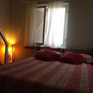 a bedroom with a bed with red pillows and a window at Chalé Village do Mirante Boiçucanga in Boicucanga +33 photos