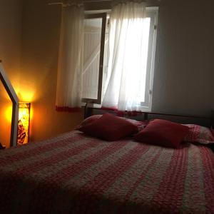 um quarto com uma cama com almofadas vermelhas e uma janela em Chalé Boiçucanga / Maresias em Boiçucanga