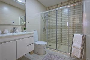 a bathroom with a toilet and a glass shower at Carla Apartamentos in Nazaré +22 photos