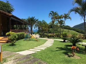 a playground in a garden with palm trees and a building at Chalé Village do Mirante Boiçucanga in Boicucanga