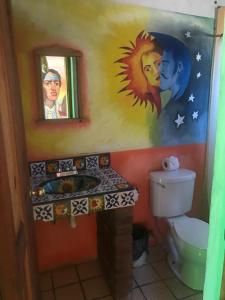 baño con aseo y una pintura en la pared en Rancho Cabañas San Isidro en Cerocahuí