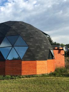 un grand bâtiment avec un toit noir sur un champ dans l'établissement Domo Trasmahue, à Villarrica