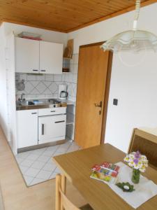 uma cozinha com uma mesa de madeira e uma cozinha com armários brancos em Haus Moni em Mauterndorf