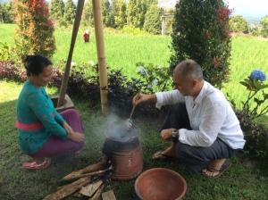 a man and a woman sitting in the grass with a pot at Puri Lumbung Cottages Restaurant & Spa Munduk in Munduk