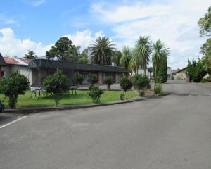 an empty street in front of a house with palm trees at Palmerston North Motel in Palmerston North