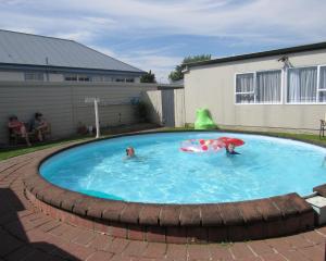 a couple of people in a pool with an umbrella at Palmerston North Motel in Palmerston North