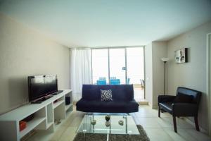 a living room with a blue couch and a tv at San Alfonso Del Mar Apartment in Algarrobo