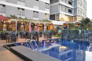 a hotel patio with a pool and tables and chairs at Grand Tara Garden Thai Hotel in Bangkok