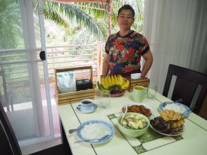 un hombre parado frente a una mesa de comida en BAANTAI HOMESTAY, en Chumphon