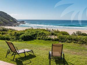 two chairs sitting on the grass near the beach at Allure on Blueys in Blueys Beach