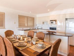 a dining room table with chairs and a kitchen at Allure on Blueys in Blueys Beach