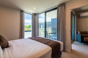 1 dormitorio con cama y vistas a un balcón en The Edgerley Suites en Auckland