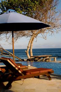 a picnic table with an umbrella next to the ocean at Jasri Bay Hideaway in Jasri