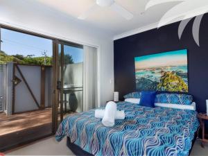 a bedroom with a bed with a painting on the wall at Aqua Apartment 4 in Blueys Beach
