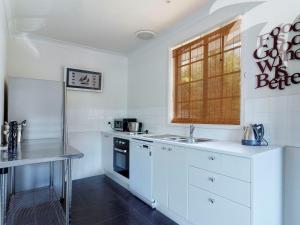 a kitchen with white cabinets and a sink and a window at Aqua Apartment 4 in Blueys Beach