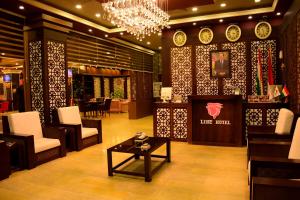 a lobby with chairs and a table and a chandelier at Lilac Hotel in Erbil