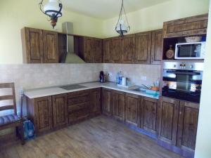 a kitchen with wooden cabinets and a stove top oven at Pensiunea Jazmin in Zetea