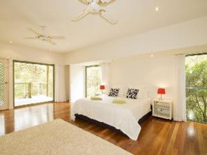 a white bedroom with a bed and a large window at Karingal just minutes from Blueys Beach in Charlotte Bay