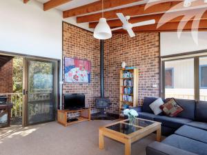 a living room with a blue couch and a brick wall at Lawsons at Blueys in Blueys Beach