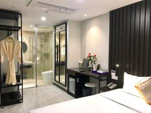 Agnes Nha Trang Hotel في نها ترانغ: غرفة نوم مع سرير ومكتب ودش