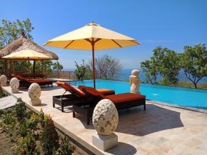 a pool with chairs and an umbrella next to a swimming pool at Samari Hill Villa in Buleleng