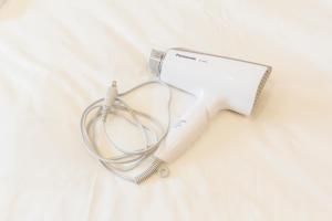 東京にあるDwell Urban 7Bの- ベッドの上に置かれた白いヘアドライヤー