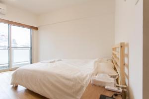 Cama blanca en habitación con ventana en Dwell Urban 7B, en Tokio