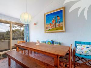 a dining room with a wooden table and chairs at Oceanside 20 Sapphire in Blueys Beach
