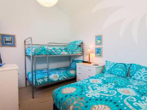 a bedroom with a bunk bed and a couch at Oceanside 20 Sapphire in Blueys Beach