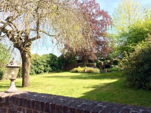 einen Garten mit einem Baum und einer Ziegelwand in der Unterkunft le carré des arts in Le Cateau