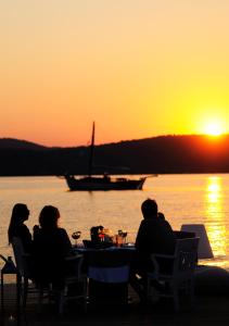 a group of people sitting at a table watching the sunset at Ekies All Senses Resort, a Member of Design Hotels in Vourvourou