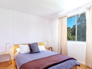 a bedroom with a bed and a large window at Pippis a Classic Beach House in Seal Rocks