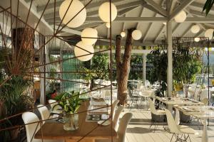 a restaurant with white tables and chairs and plants at Ekies All Senses Resort, a Member of Design Hotels in Vourvourou