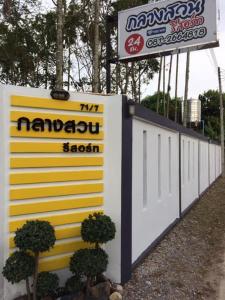 een witte en gele muur met een bord en enkele planten bij Klangsuan Resort กลางสวน รีสอร์ท แกลง in Ban Phlong Chang Phuak